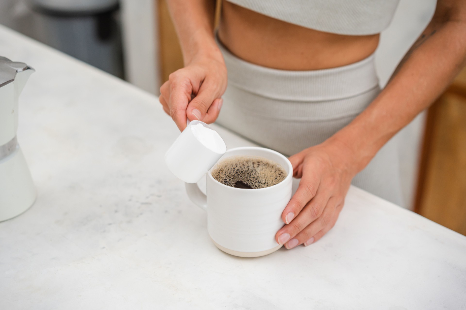Unrecognizable woman adding protein powder in a coffee